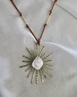 Collar con dije de bronce con forma de sol y centro de nácar, engarzado en un cordón de cuero marrón con detalles de bronce.