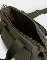 Cartera tipo tote color blanco hueso, con doble asa corta negra y correa larga negra regulable y desmontable. Tiene cierre superior, bolsillos laterales y tag de goma con el logo de la marca.