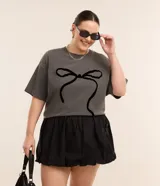 Remera gris de algodón con cuello redondo y manga corta. Presenta un estampado central de un lazo negro.