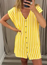 Vestido corto de tejido de punto, con diseño de rayas verticales amarillas y blancas. Presenta escote en V y abotonadura frontal con botones oscuros. Tiene mangas cortas tipo solapa.