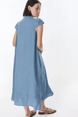 Vestido camisero celeste de lino, corte midi, con cuello camisero, mangas cortas con volados y abotonadura frontal.