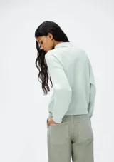 Chaqueta color verde agua con cuello camisero, cierre frontal con botones, dos bolsillos de parche con solapa en el pecho y mangas largas.