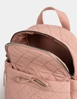 Mochila rosa claro de tela deportiva acolchada con diseño de rombos. Tiene asa de mano, correas regulables, cierre superior, bolsillo frontal con lazo decorativo y bolsillos laterales con lazos.