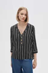 Camisa holgada de viscosa con estampado de rayas verticales en blanco y negro, cuello en V y mangas 3/4 con detalle de botones.
