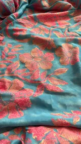 Vestido largo de verano con estampado floral en tonos celeste y rosado. Presenta un escote halter con tirantes finos que se anudan en el cuello y un corte imperio con frunces que genera una falda con mucho vuelo y volados en los ruedos inferiores.