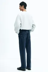 Pantalón de jean azul oscuro, de corte holgado desde la cadera hasta el ruedo, con pierna ancha y tiro bajo.
