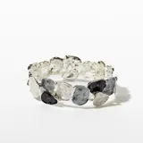Pulsera rígida plateada con eslabones irregulares en tonos blanco, gris y negro.