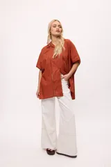 Camisa blanca de manga corta con cuello clásico, corte holgado y detalle de calado vertical en el frente.