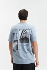 Remera celeste de manga corta con cuello redondo. Presenta un estampado en la espalda con imágenes de arquitectura y texto en color negro.