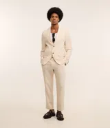 Conjunto de saco y pantalón color beige, confeccionado en lino y viscosa. El saco es de corte clásico con solapas y cierre de dos botones. El pantalón es de corte relajado con cintura con trabillas y bolsillos laterales.