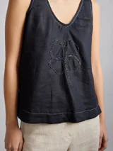 Top color rosa pálido de lino con cuello en V y bordado de un trébol de cuatro hojas en el centro.