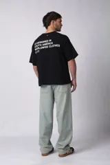 Remera negra de algodón grueso, corte cuadrado y manga corta. Estampado frontal pequeño con tres círculos concéntricos y letras en su interior. Estampado trasero grande con la frase "Designed in South America, Worldwide Clothes".