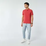 Chomba de piqué color rojo con cuello clásico y borde blanco, de corte recto y manga corta.