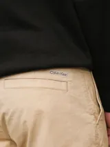 Pantalón chino color beige confeccionado en sarga de algodón elástica suave, de corte regular y pierna estrecha en el tobillo.