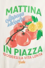 Remera oversized de algodón color crema con estampado de tomates y limones, y texto en italiano en verde y azul.