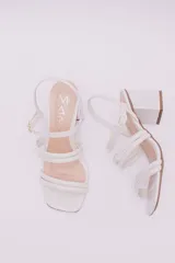 Sandalias de ecocuero charolado color negro, con punta cuadrada, dos tiras horizontales sobre el empeine, pulsera con hebilla al tobillo y taco cuadrado.