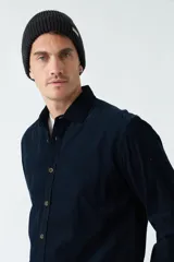 Camisa de pana color verde militar, de corte regular, con cuello clásico y cierre frontal con botones.