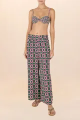 Pantalón largo de corte palazzo, con cintura elástica y estampado de cadenas entrelazadas en tonos verde oscuro, blanco y fucsia.