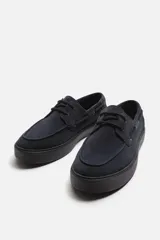 Zapato náutico de cuero color azul marino con cordones finos y suela plana.