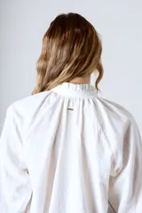 Blusa celeste con rayas verticales blancas, cuello mao y mangas largas abullonadas con puños elásticos.