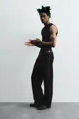 Pantalón de jean gris oscuro, corte amplio, con cinco bolsillos, efecto lavado y cierre frontal con cremallera y botón.