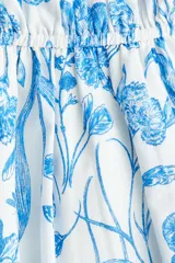 Vestido corto blanco con estampado floral azul, escote cuadrado con volados, mangas cortas abullonadas con elástico y cintura elastizada.
