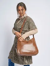 Bandolera tipo hobo de cuero sintético color marrón con correa de hombro ajustable. Tiene un logo triangular metálico en el frente.