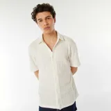 Camisa de manga corta color beige con textura de punto calado, cuello clásico y cierre frontal con botones.