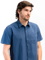 Camisa de manga corta color beige, confeccionada en 100% algodón, con cuello clásico, cierre frontal con botones y bolsillo en el pecho.