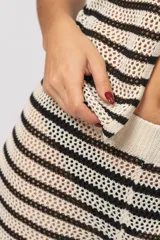 Chaleco de punto calado a rayas horizontales en tonos crudo y negro, con escote en V y cierre frontal de dos botones.