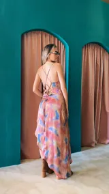 Vestido midi con estampado tie-dye en tonos rosado, azul y beige, con escote drapeado, breteles finos y corte irregular.