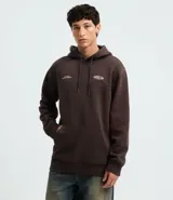 Saco con capucha de algodón y poliéster, color marrón oscuro, con bolsillo canguro frontal y cordón de ajuste. Presenta un pequeño logo bordado en el pecho izquierdo y un gráfico ovalado en el centro del pecho.