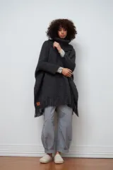 Poncho tejido de lana color gris oscuro, con cuello alto y flecos en el ruedo.