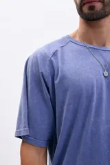 Remera de manga corta con mangas ranglán, color azul con efecto lavado o acid wash. Presenta cuello redondo y corte holgado.