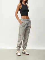 Pantalón jean gris de corte recto, con bolsillos laterales y tobillos ajustados con elástico.