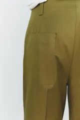 Pantalón color beige de corte ancho, con tiro medio, trabillas en la cintura y raya planchada.