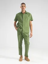 Pantalón de vestir color crema, confeccionado en tejido ligero de algodón con textura seersucker. Tiene corte recto, bolsillos laterales y traseros, cierre con botón y cremallera, y parche con logo de la marca.