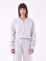 Campera gris melange con capucha y cierre frontal, corte cropped y mangas largas.
