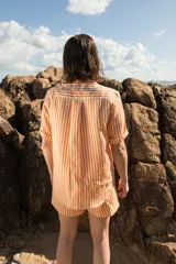 Camisa de lino a rayas verticales color naranja y blanco, de manga corta y corte oversize. Presenta bordados con motivos playeros en el frente y la espalda.