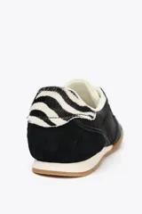 Zapatillas deportivas negras con detalle de estampado animal en la parte trasera, suela color caramelo y ajuste con cordones.