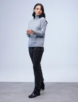 Polera de punto fino marca Nienty, color blanco, con cuello alto volcado y mangas largas con detalle de tajo en los puños.