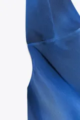 Vestido largo de seda azul con estampado degradado que simula ondas o nubes. Presenta escote halter con tiras finas ajustables y aberturas laterales en la cintura.