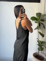Vestido largo negro con breteles finos, escote en V y detalles de encaje en el escote y en el ruedo.