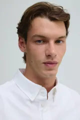 Camisa blanca de algodón Oxford con cuello americano, tapeta clásica, bolsillo superior abierto y canesú en la espalda. Mangas largas con puños abotonados y bajo levemente redondeado. Corte estándar.