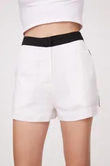Short de lino blanco con cintura alta negra y corte recto.