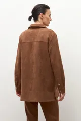 Camisa de manga larga color tostado, con cuello camisero y botones frontales. Presenta bolsillos de parche en el pecho.