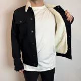 Chaqueta de franela a cuadros en tonos marrón, blanco, azul y naranja, con cuello de corderito blanco, cierre con botones a presión, bolsillos en el pecho con solapa y bolsillos laterales.