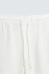 Pantalón verde oscuro de algodón con textura, corte recto, cintura elástica ajustable con cordón, bolsillos laterales y traseros de vivo.