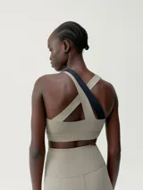 Top deportivo bicolor con asimetría, sujeción media-alta y tirantes cruzados. Confeccionado en tejido Shape_Tech con interior de mesh y copas extraíbles.