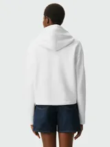 Buzo con capucha color verde oliva, con cordones ajustables y bolsillo tipo canguro. Logo bordado de corazón negro en el pecho. Corte holgado.